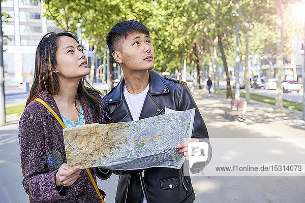 Tourist couple visiting the city and holding a map  Barcelona  Spain