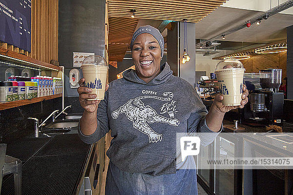 Happy young woman showing milkshakes in a cafe