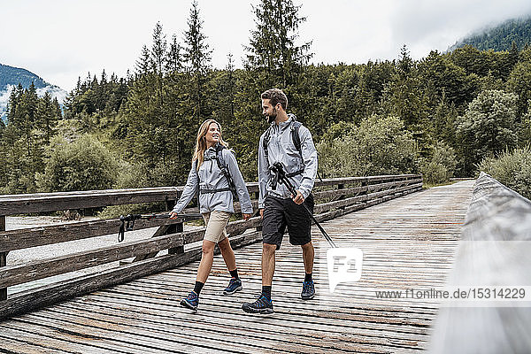 Young couple on a hiking trip walking on wooden bridge  Vorderriss  Bavaria  Germany