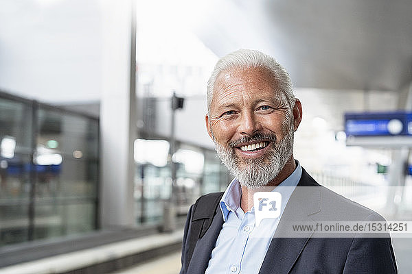 Portrait of happy mature businessman at the station platform