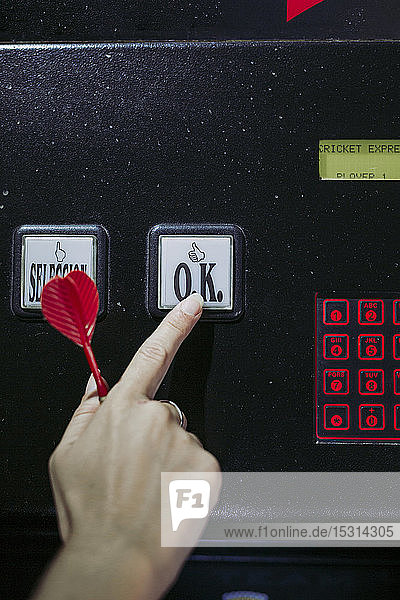 Close-up of woman's hand switching on electronic dartboard