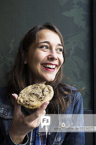 Smiling woman looking sideways and eating cookie