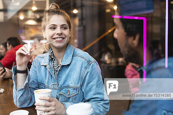 Portrait of smiling young woman in a coffee shop looking at young man