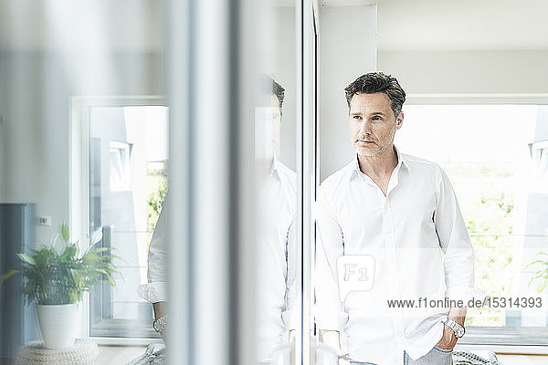 Serene man leaning on window at home