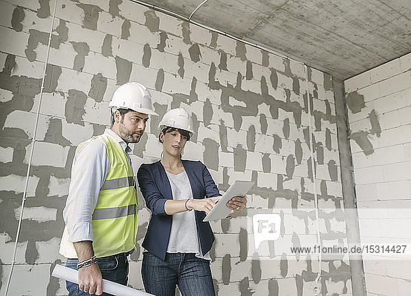 Zwei Architekten benutzen Tablett  während sie auf der Baustelle stehen