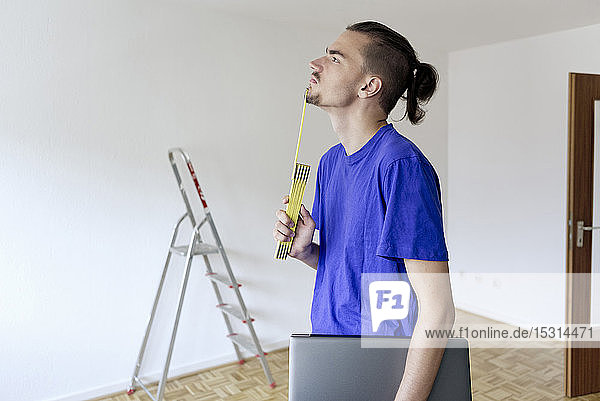 Young man with pocket rule in an empty apartment