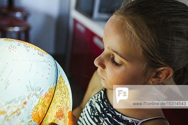 Curious girl looking at illuminated globe