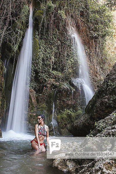 Young woman posing at a waterfall with burned skin