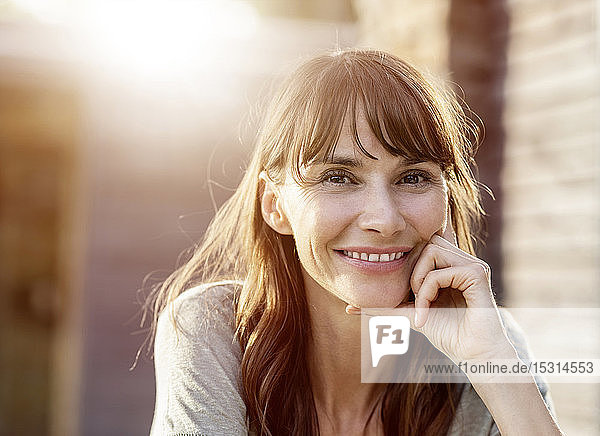 Porträt einer lächelnden brünetten Frau im Gegenlicht