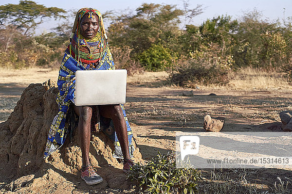 Traditional Muhila woman  wearing sneakers neakers working on her laptop  Kehamba  Chibia  Angola