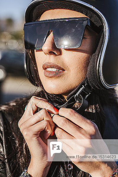 Portrait of motorcyclist with sunglasses putting on helmet