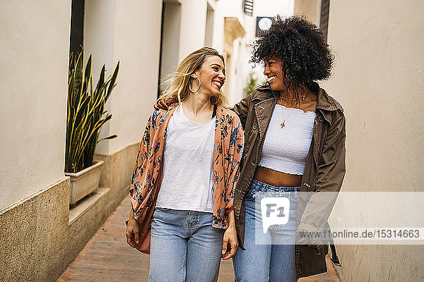 Multikulturell lachende Frauen gehen in der Stadt spazieren
