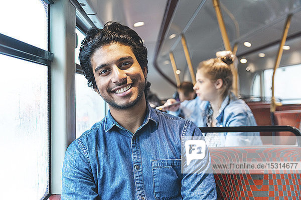 Porträt eines glücklichen jungen Mannes  der mit dem Bus reist  London  UK