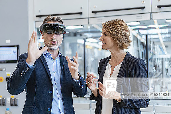 Geschäftsmann mit AR-Brille und Geschäftsfrau in einer modernen Fabrik