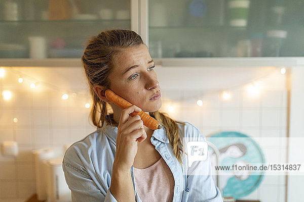 Junge Frau benutzt Karotte als Telefon zu Hause