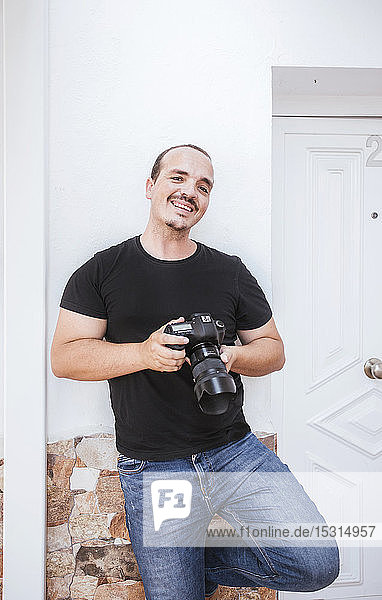 Portrait of smiling man hoding a camera