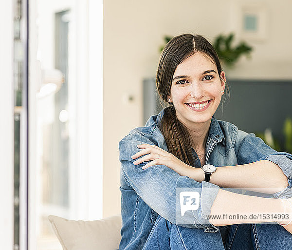 Portrait of smiling young woman wearing denim shirt at home