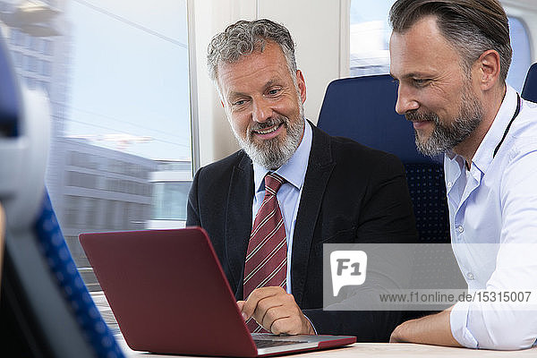 Businessmen traveling by train  working on laptop