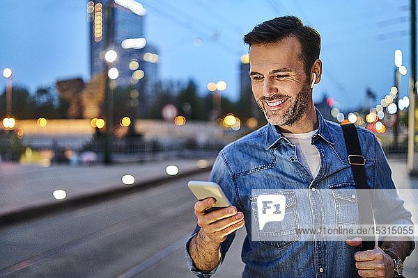Man standing with smartphone waiting for evening commute after work