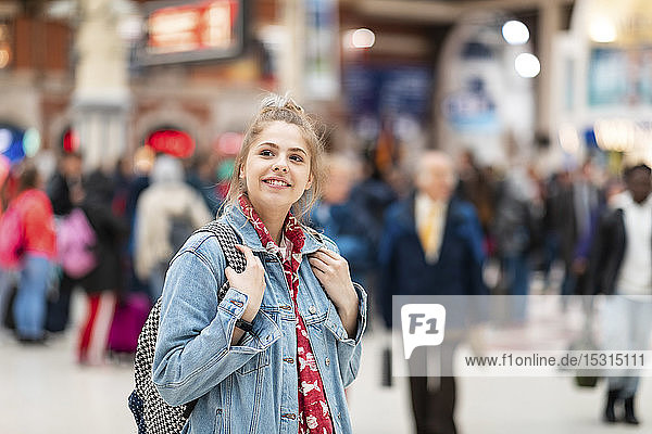 Lächelnde junge Frau am Bahnhof