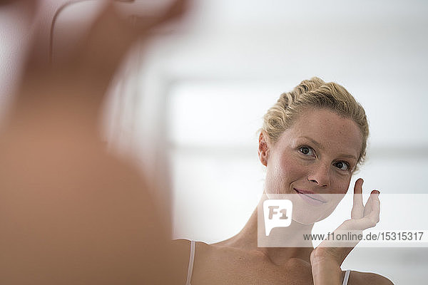 Portrait of beautiful blond woman applying eye cream
