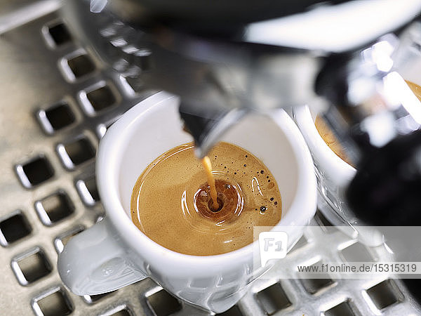 Espresso fließt in eine Espressotasse