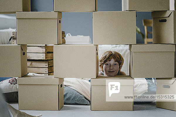 Porträt eines lächelnden Jungen mit Pappkartons im neuen Zuhause