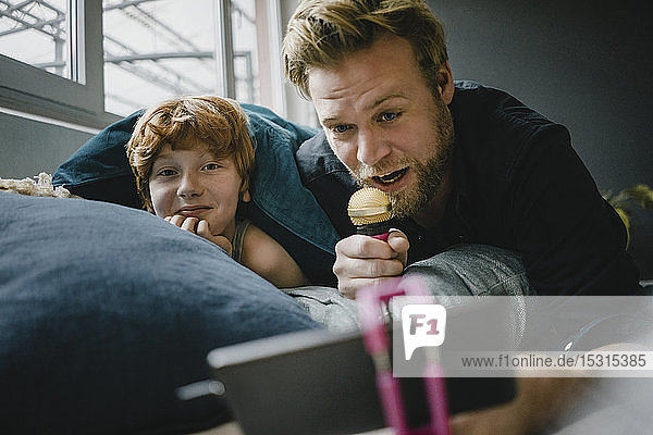 Father and son with smartphone and microphone at home