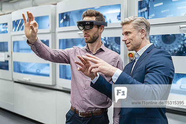 Two businessmen with AR glasses in a modern factory