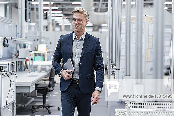 Confident businessman with tablet in a modern factory