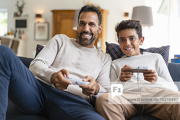 Happy father and son playing video game on couch in living room