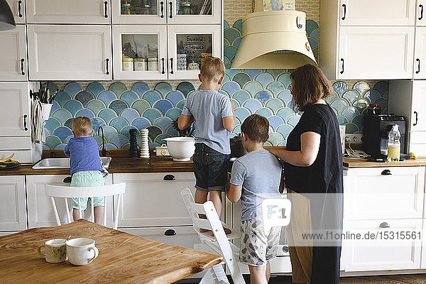 Mother cooking with her three sons in the kitchen