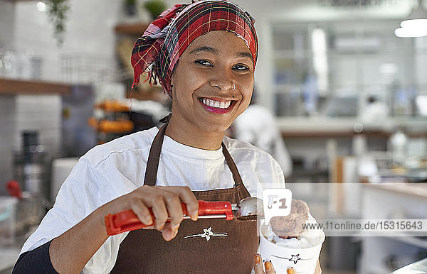 Young woman working in ice cream parlour  filling cup with icecream