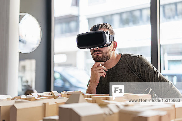 Man with architectural model in office wearing VR glasses