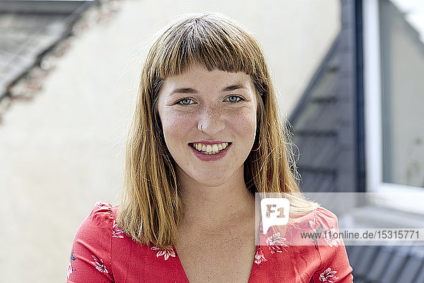 Bildnis einer lächelnden jungen Frau mit Sommersprossen und Nasenpiercing