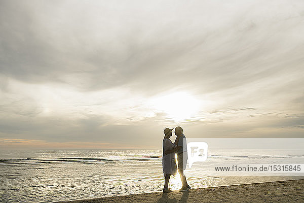 Silhouette eines älteren Ehepaares  das sich bei Sonnenuntergang am Strand gegenüber steht  Liepaja  Lettland