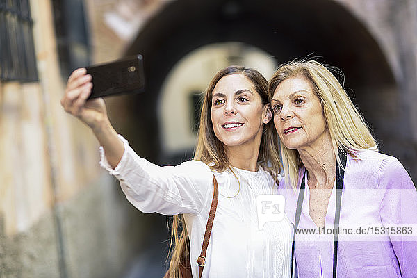Frau  die mit ihrer Mutter in der Stadt ein Selfie macht