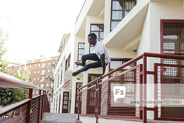 Young man jumping across a fence in the city