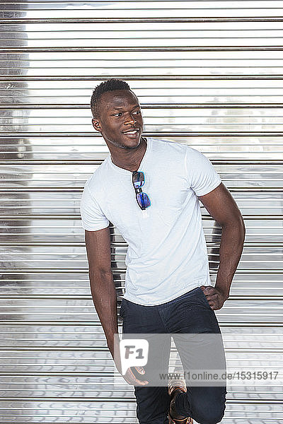 Portrait of confident young man wearing white t-shirt at a roller shutter