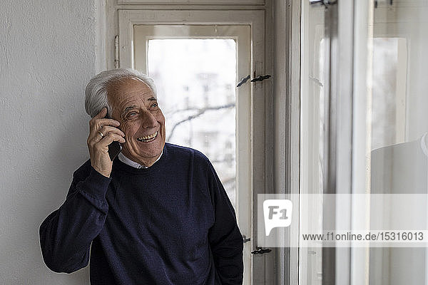 Happy senior man on cell phone at home