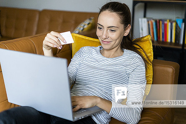 Young woman on couch at home shopping online