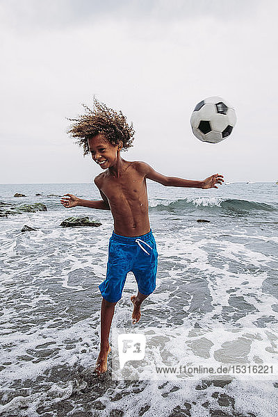 Boy playing with a football on the beach