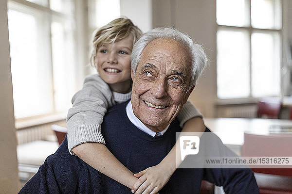 Happy grandson embracing grandfather at home