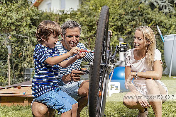 Familie repariert gemeinsam ein Fahrrad im Garten