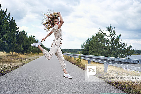 Cheerful woman jumping on rural road