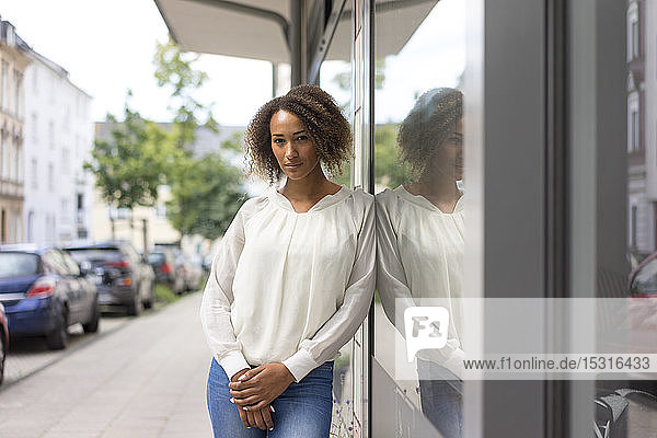 Porträt einer jungen Frau  die sich gegen ein Schaufenster lehnt
