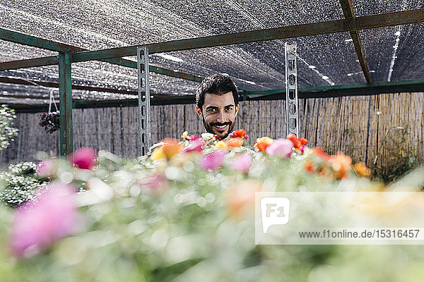 Porträt eines lächelnden Gärtners in einem Gewächshaus mit Blumen