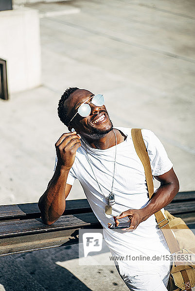 Happy young man with earphones and mobile phone in the city