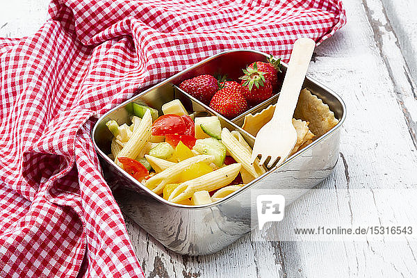 Pasta salad  strawberries and crackers in lunch box on wooden table