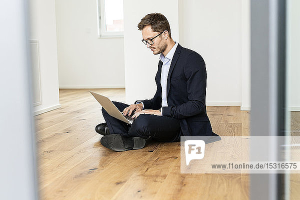 Geschäftsmann sitzt mit Laptop auf dem Boden